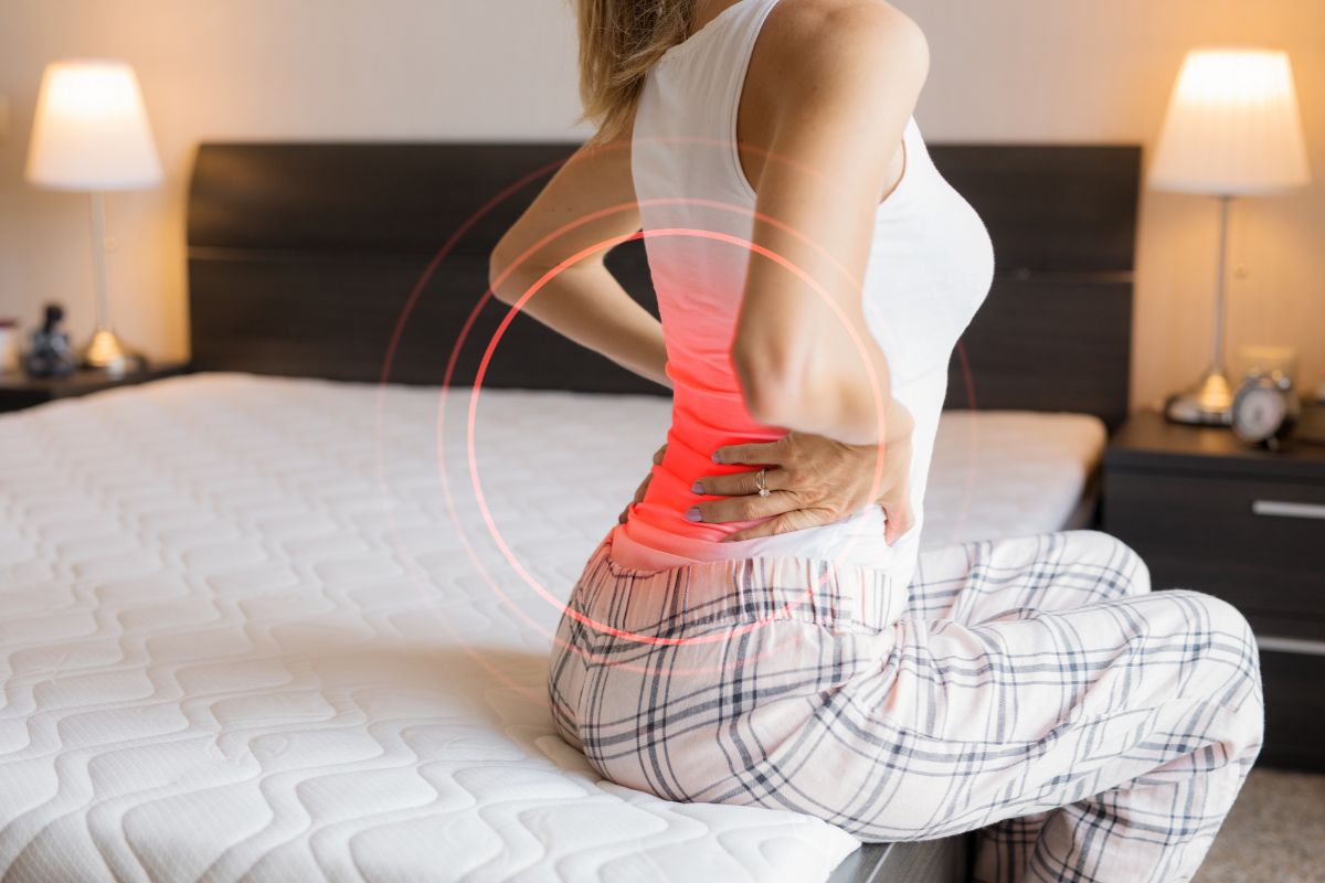 Woman experiencing lower back pain that may benefit from a firmer mattress for support