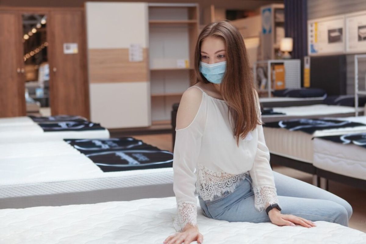 Woman testing a medium mattress in a showroom to find the best firmness level for relieving back pain