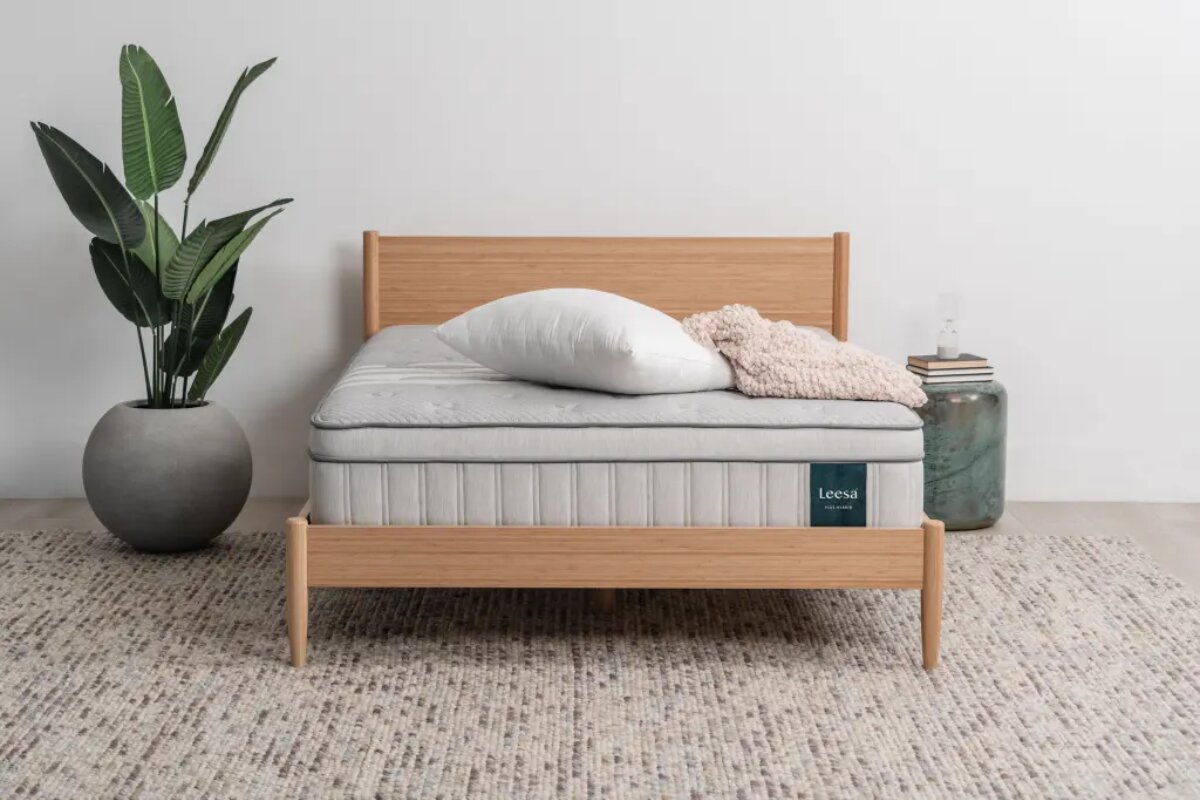The Leesa Natural Hybrid Mattress with a plant next to it.
