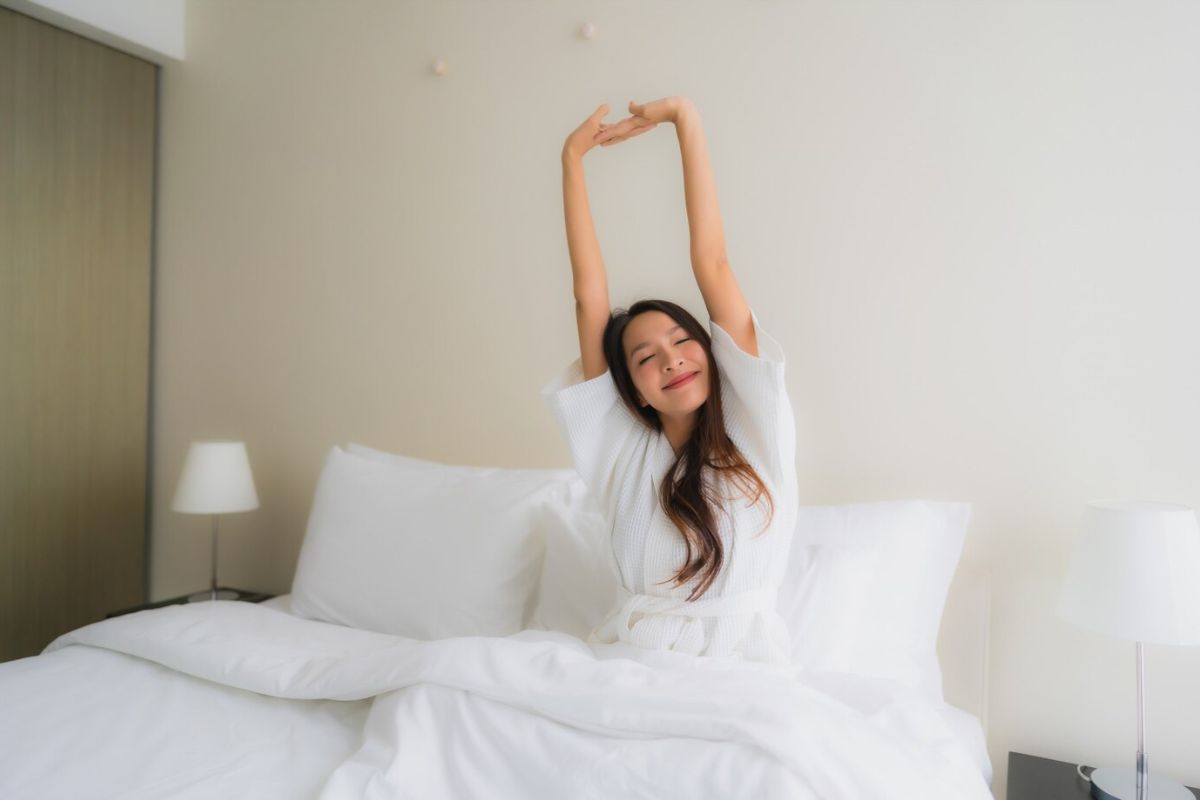 Woman stretching after waking up on a medium mattress designed for balanced pressure relief and comfort