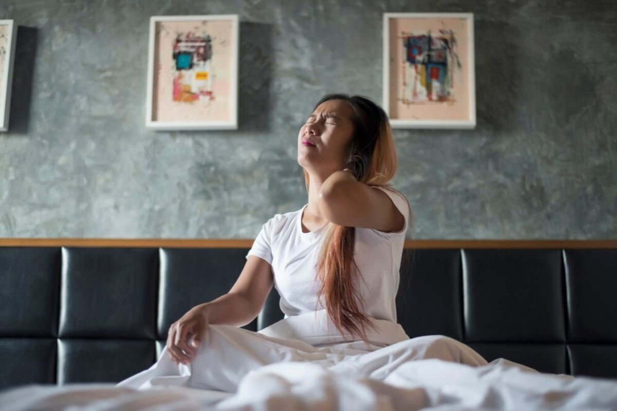 What Is a Soft Mattress? Person experiencing neck discomfort after sleep, highlighting how the wrong mattress softness level can contribute to aches and poor spinal support
