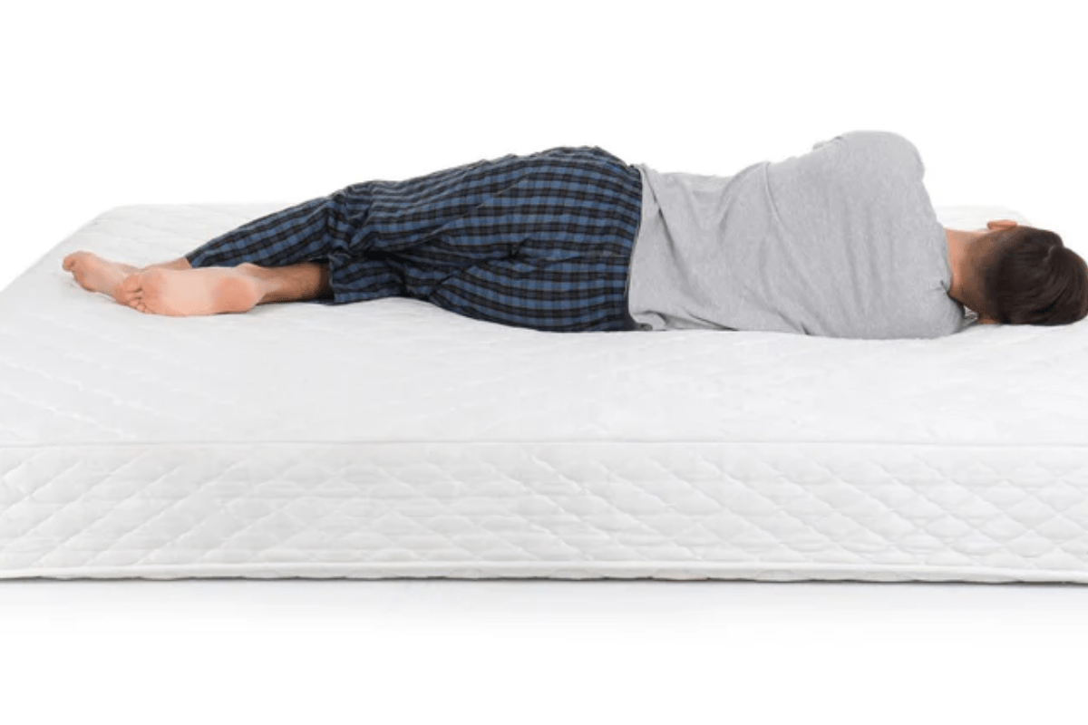 Man Sleeping on His Side on a Quilted White Mattress how to tell if a mattress is too soft or firm