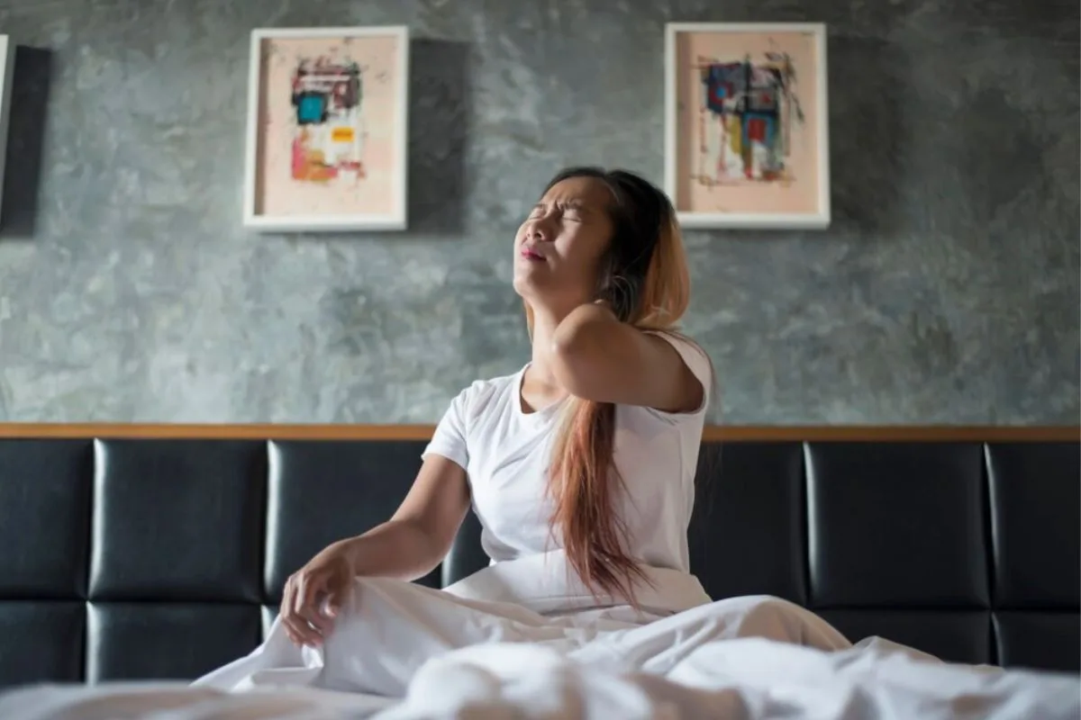 Woman waking up with neck pain that may be caused by using the wrong mattress firmness level