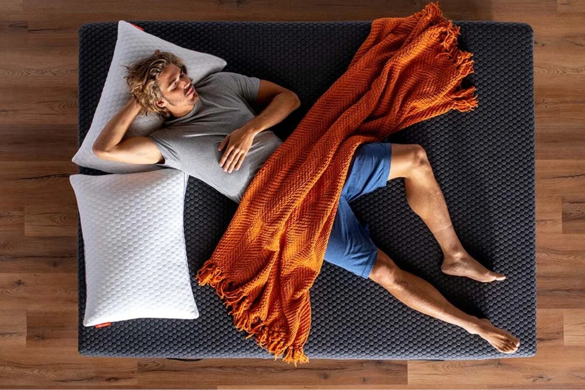 A man lying down on the Layla Hybrid Mattress.