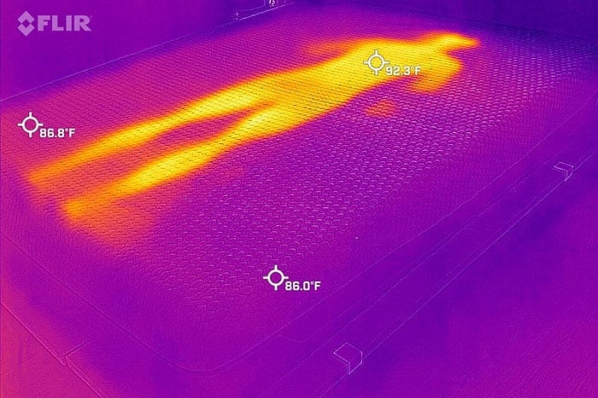 A heat image of a person laying on a bed, very visible.