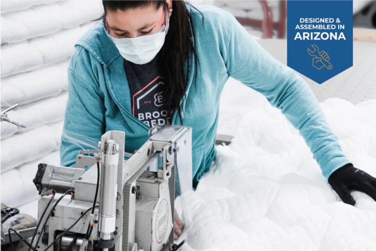 A technician working on a mattress with a designed and assembled in arizona tag.
