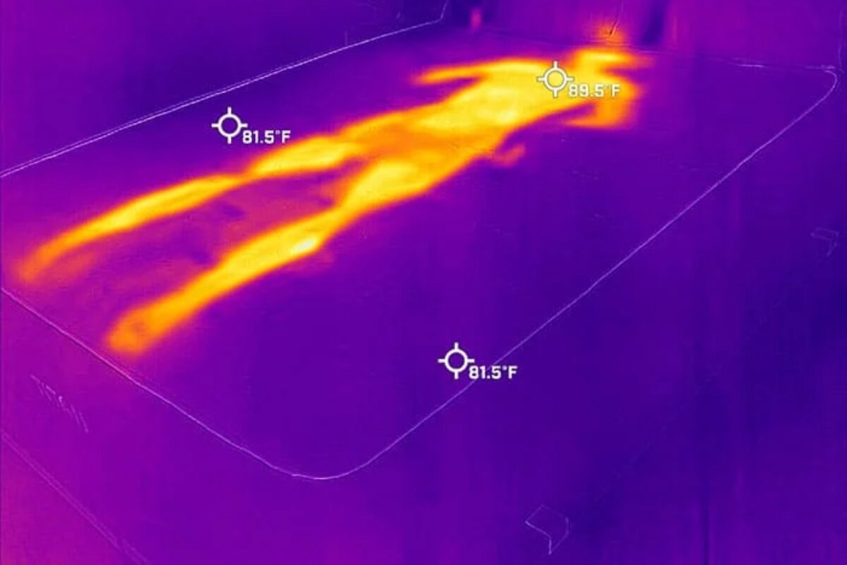 A heat image of a person laying on a mattress, very visible.