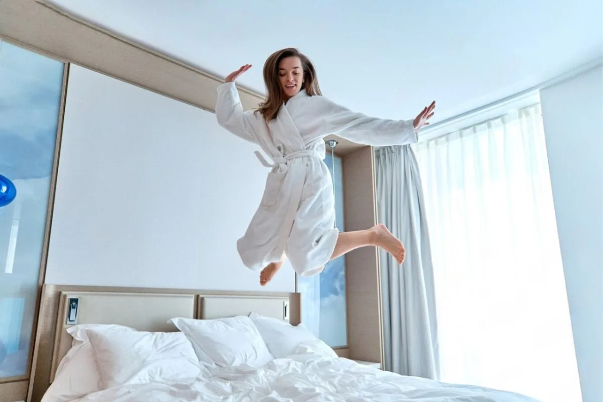Woman jumping on a bed to demonstrate the responsive bounce and motion support of a hybrid mattress