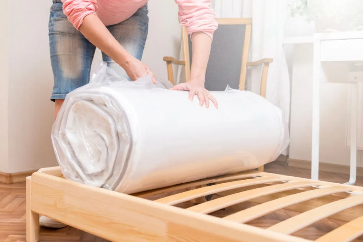 Person unboxing a compressed hybrid mattress to demonstrate the recommended setup process after delivery