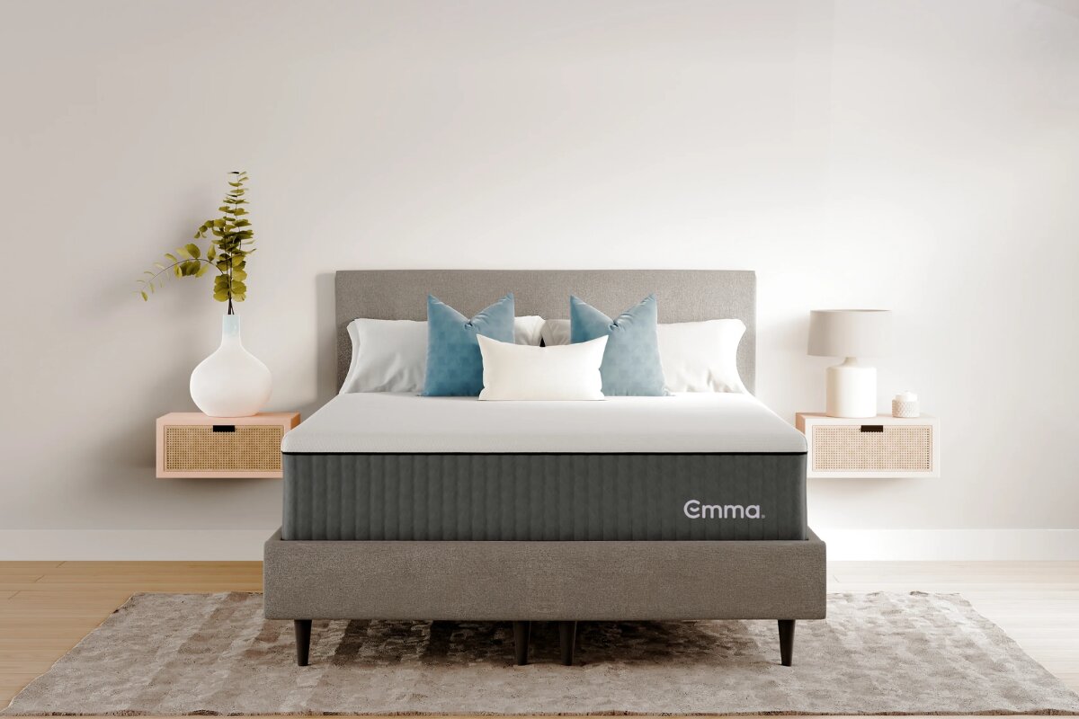 emma elite mattress on modern upholstered bed frame with white bedding and blue accent pillows in minimalist bedroom