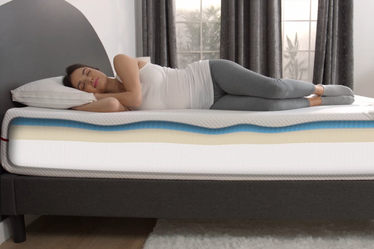 A woman sleeping on an allfoam bed with the layers exposed.