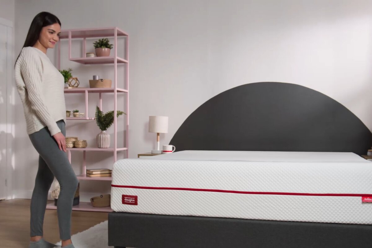 A woman standing beside a Douglas Summit Mattress.