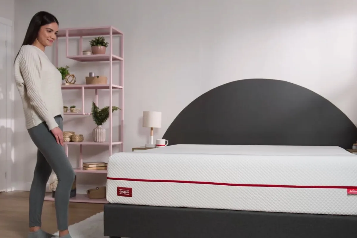 A woman standing beside a Douglas Summit Mattress.