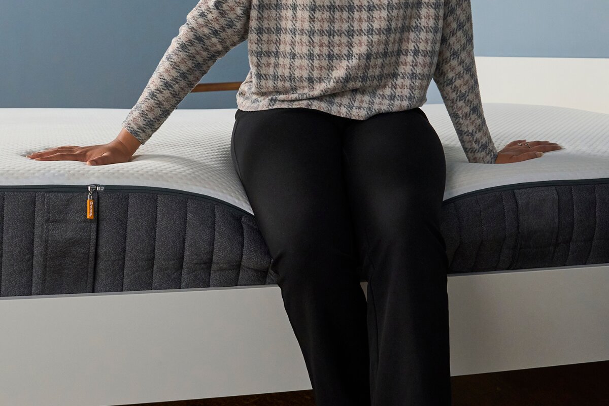 person sitting on emma elite mattress edge showing support and response time