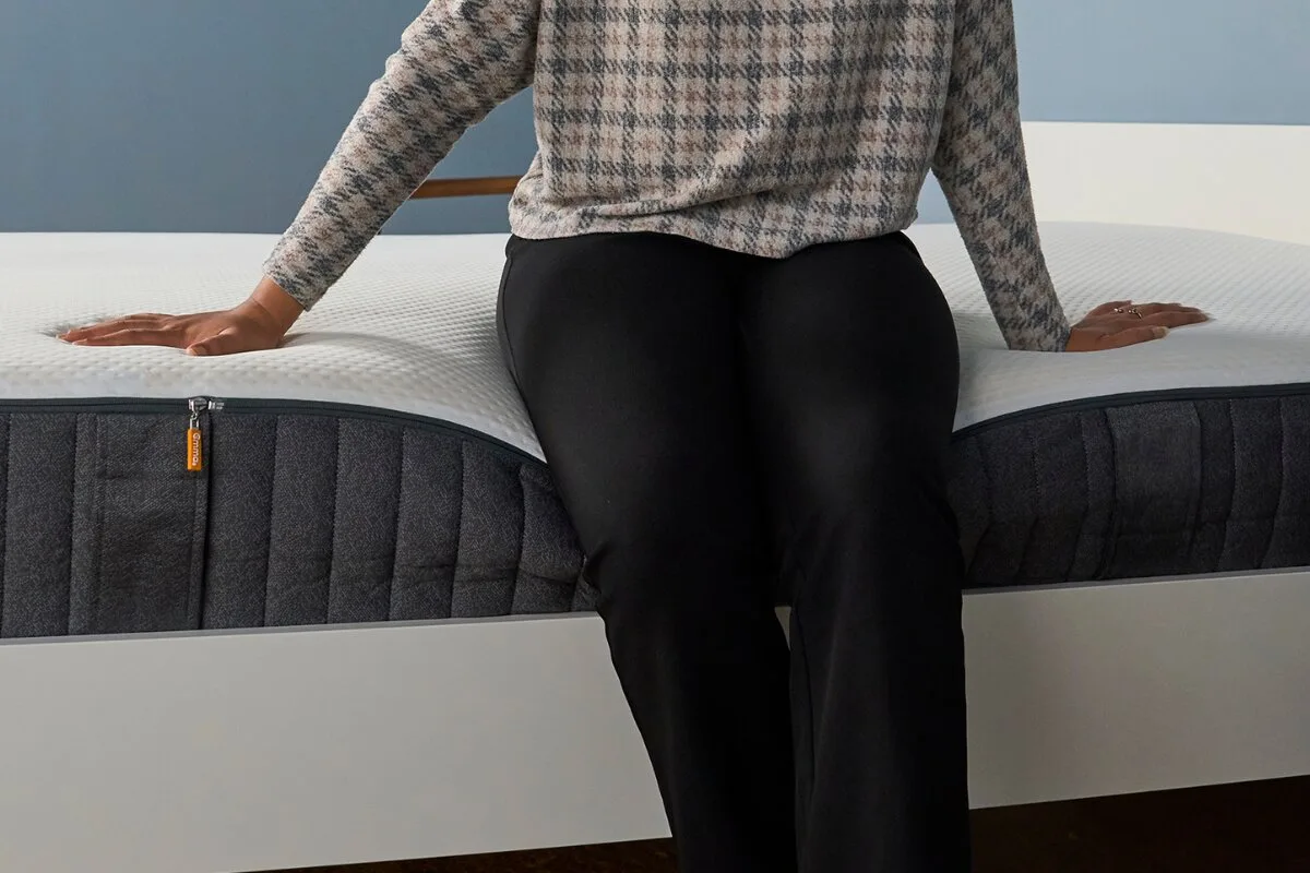 person sitting on emma elite mattress edge showing support and response time