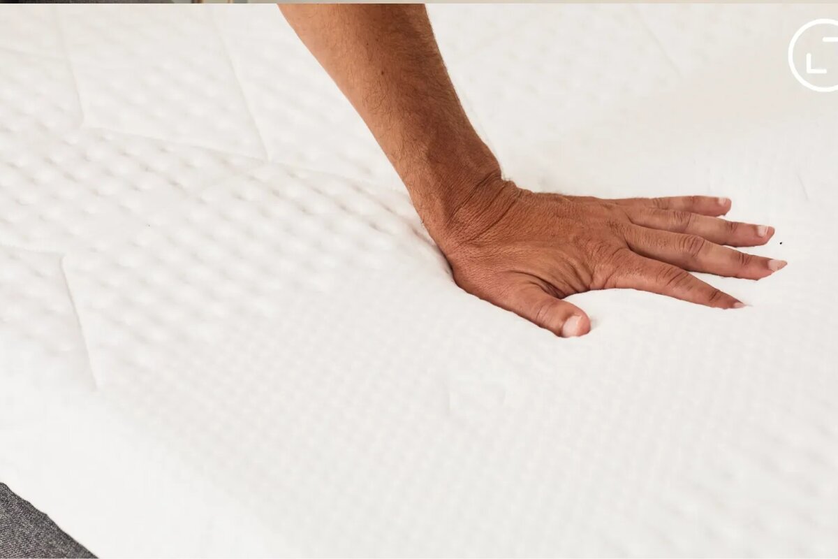 hand pressing into emma elite mattress surface showing foam sinkage and pressure relief