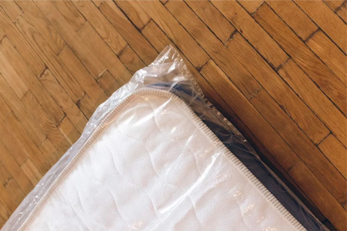 Hybrid mattress wrapped in protective plastic after compression, showing how mattresses are sealed to reduce size during moving or shipping.