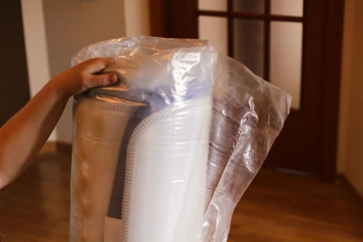 Compressed hybrid mattress enclosed in plastic wrap, illustrating the final compact form after compression for easier moving and handling.