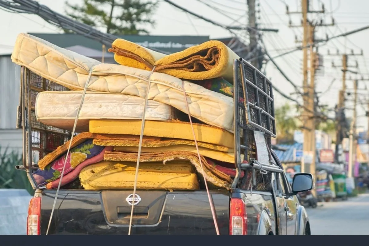 Used mattresses loaded onto a truck for transport, demonstrating mattress recycling, donation, or disposal services for memory foam mattresses