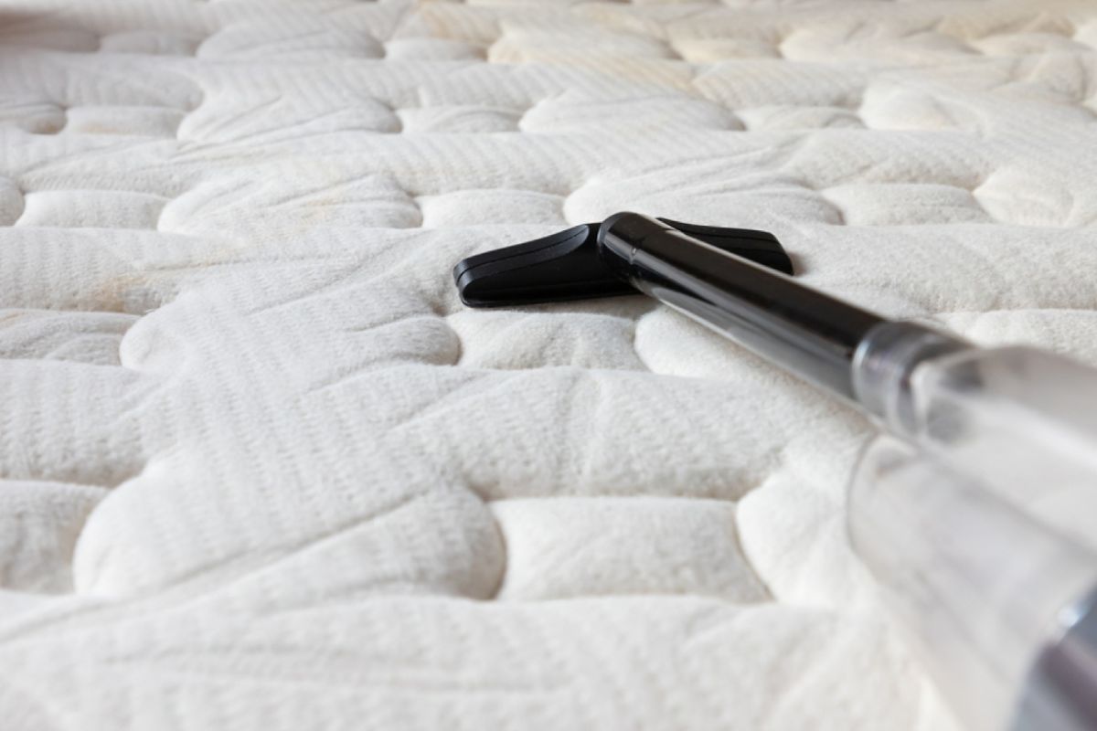 Vacuuming a memory foam mattress surface to remove moisture, dust, and debris before the drying process