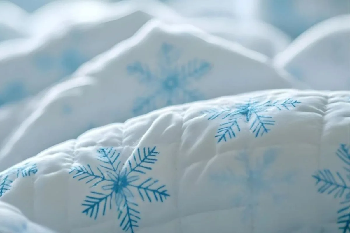 Cooling mattress topper with snowflake patterns, showing a common bedding accessory used to make a memory foam mattress sleep cooler