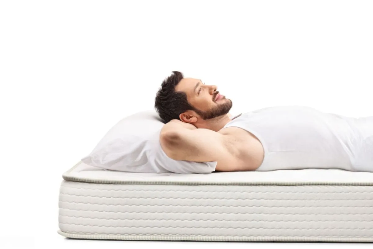 Back sleeper lying on an innerspring mattress, demonstrating spinal support and comfort considerations when choosing a mattress