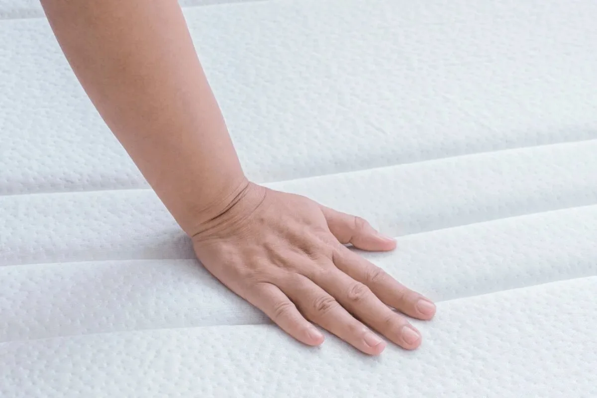 A person pressing on a memory foam mattress.