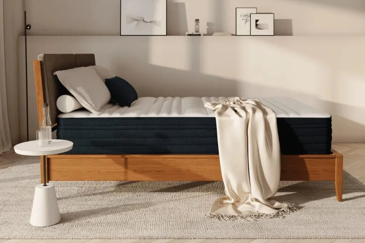 A side view of the Origin Hybrid Pro Mattress with pillows and a blanket.