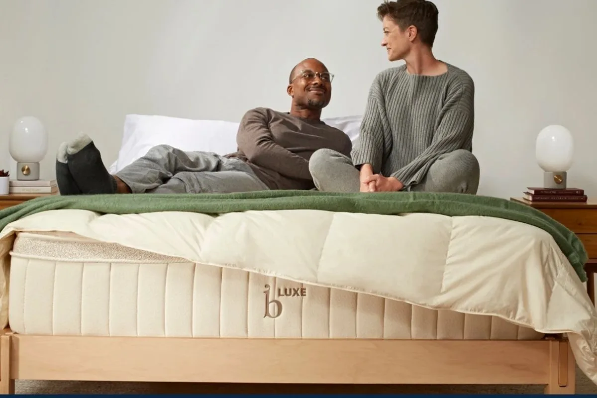 Sleeping on Your Stomach: Does it Have Any Negative Effects? Couple sitting on a supportive mattress, representing the importance of choosing the right mattress for stomach sleepers seeking better spinal support