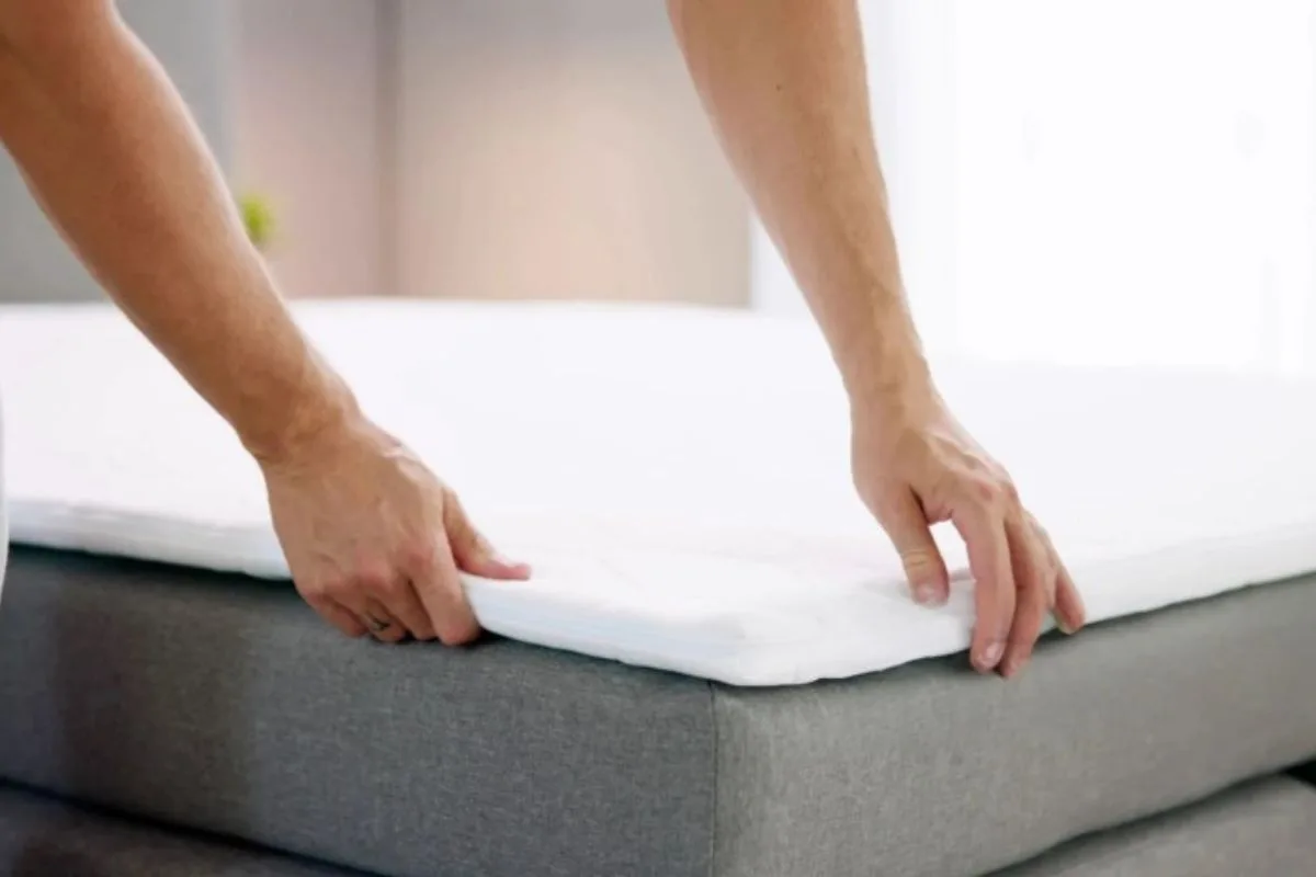 How Long Does a Memory Foam Mattress Take to Expand? Person placing a mattress protector on a memory foam mattress, highlighting the importance of waiting for full expansion before regular use and bedding setup
