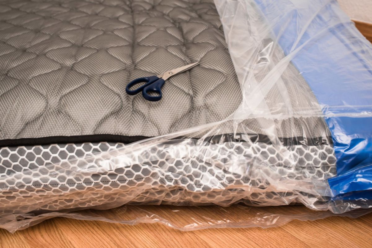 Compressed memory foam mattress being unboxed and unwrapped, illustrating the first stage of expansion after delivery