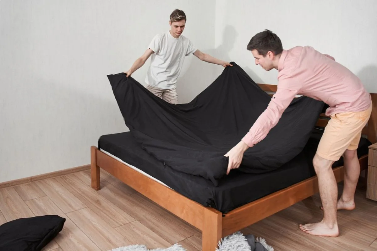 How Often Should You Turn an Innerspring Mattress? People changing bedding on a mattress, showing part of a mattress care routine that includes inspecting and rotating an innerspring mattress as needed