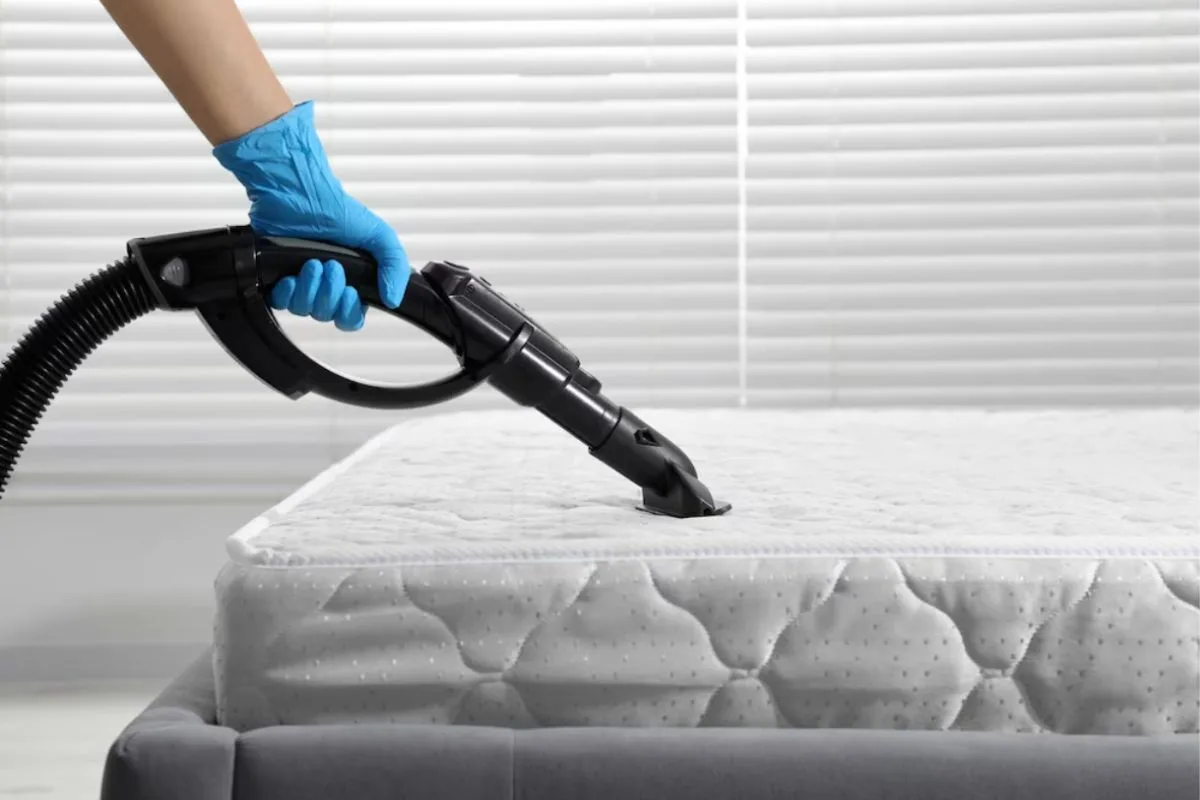 Vacuuming a memory foam mattress surface to remove dust, debris, and allergens before treating mattress stains