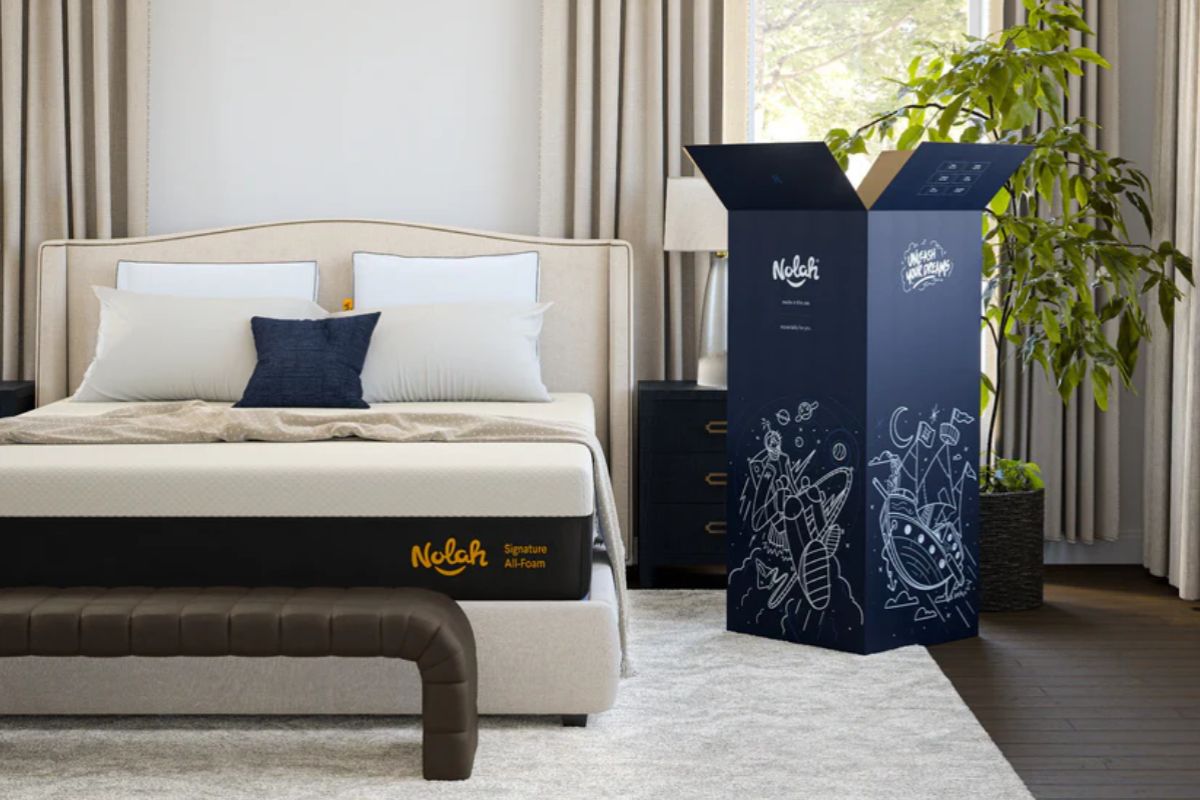 Nolah Signature 12 mattress and shipping box in a bedroom, illustrating the unboxing and setup experience customers can expect during the trial period