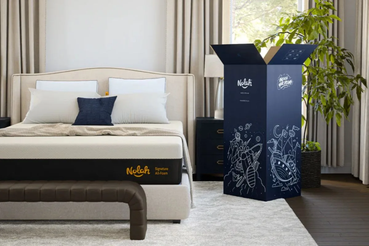 Nolah Signature 12 mattress and shipping box in a bedroom, illustrating the unboxing and setup experience customers can expect during the trial period