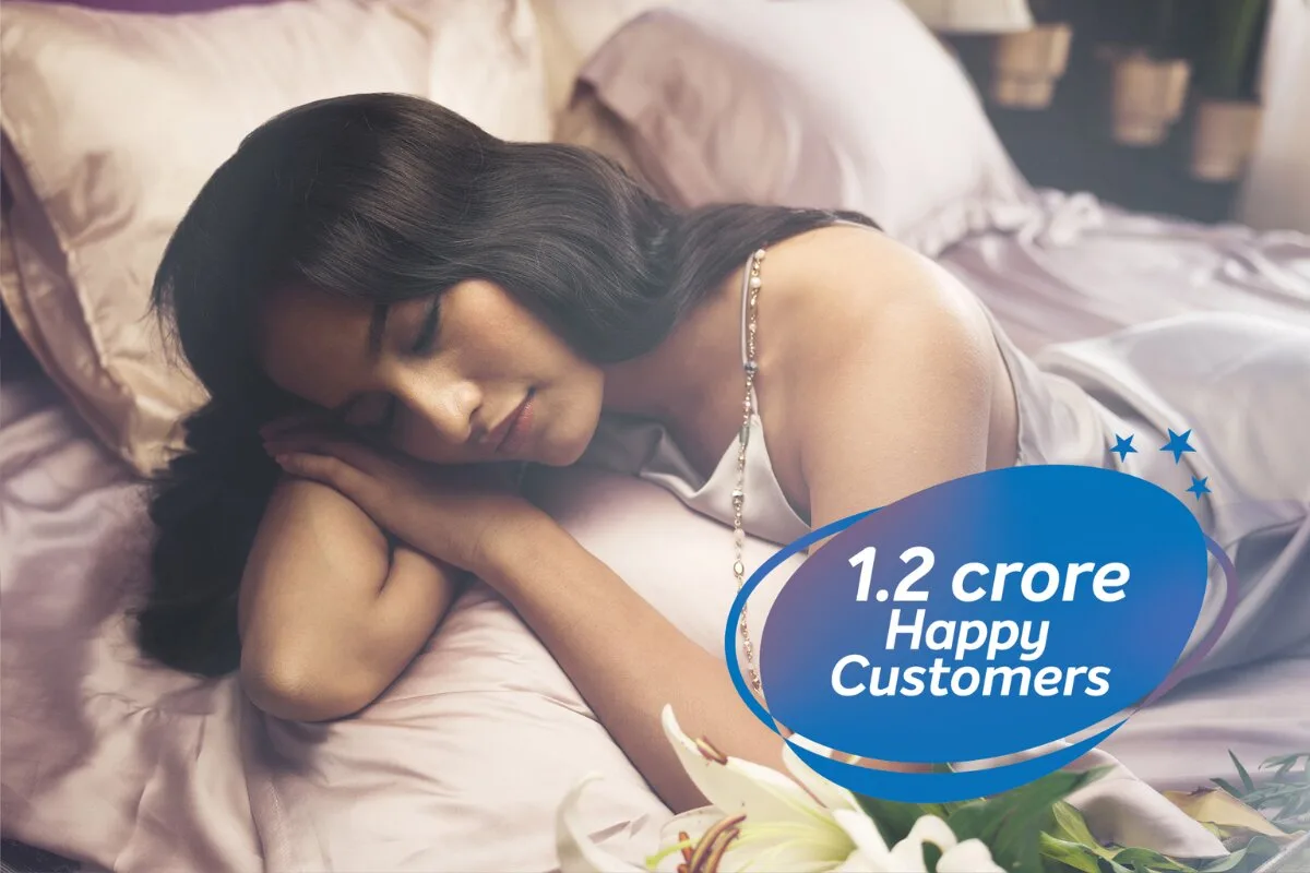 A woman laying down the Sleepwell Pro Nexa Classic mattress with a 1.2 crore Happy customers tag.
