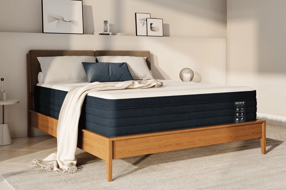 Origin Hybrid Pro mattress on wooden bed frame in modern bedroom with neutral decor and pillows