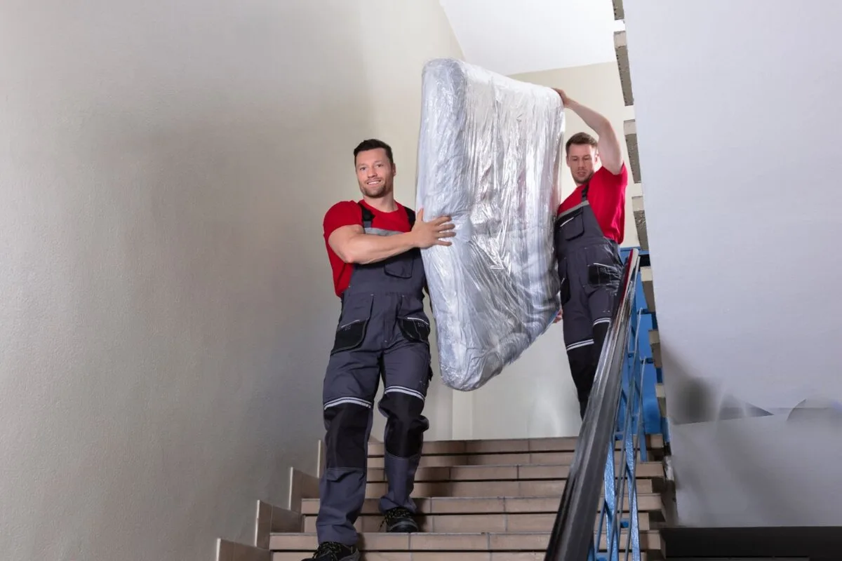2 men moving a mattress down the stairs.