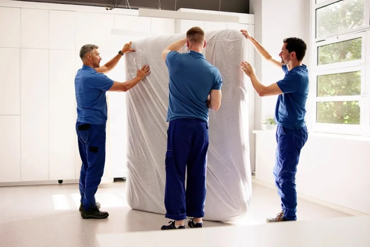 How to Move a Latex Hybrid Mattress? 3 men unpacking a mattress.