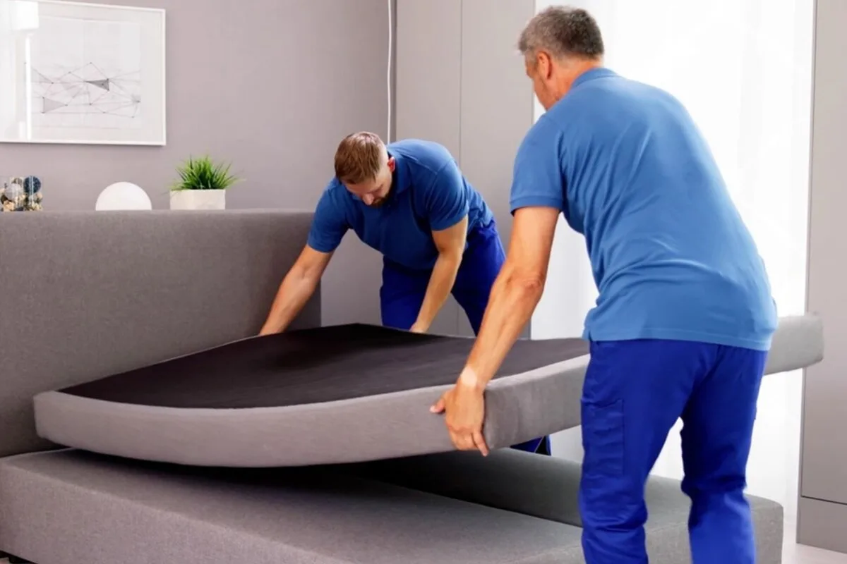 How to Move a Latex Mattress? 2 men wearing blue moving a mattress.