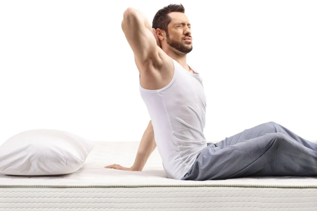 A man holding his neck in bed.