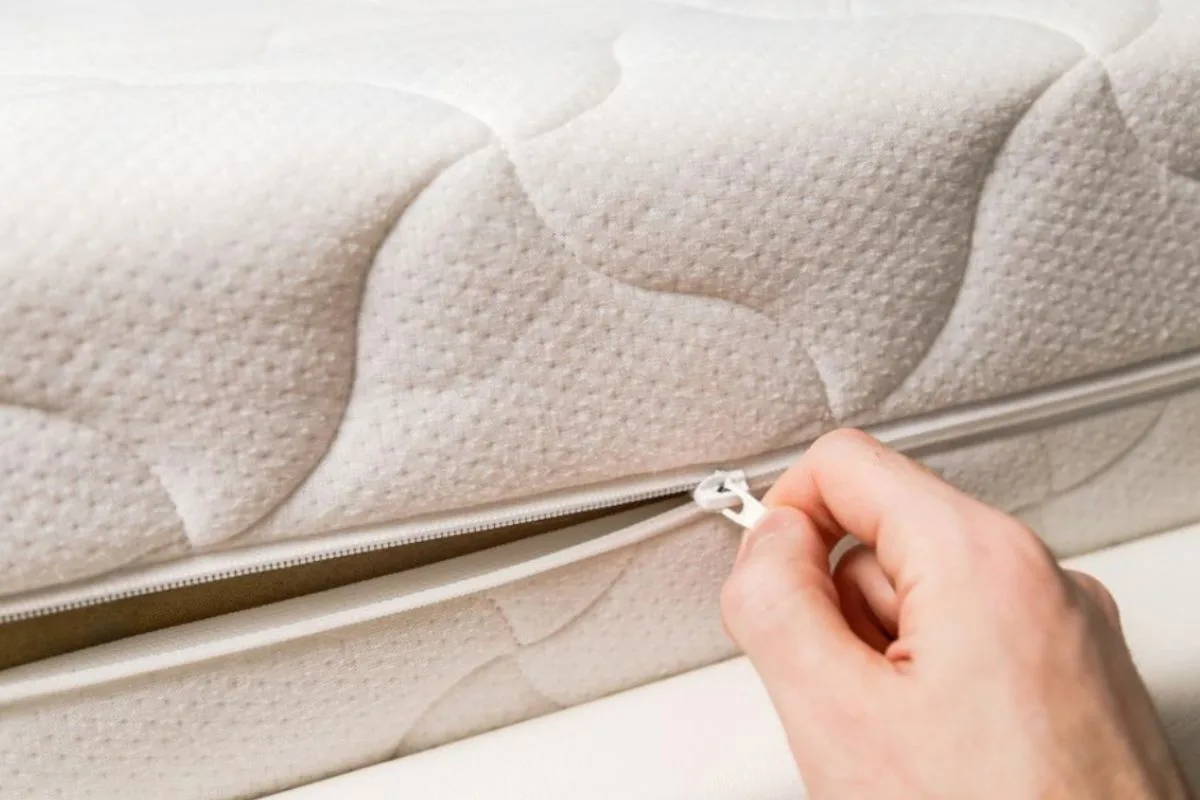 Unzipping a latex hybrid mattress cover to reveal the internal construction and layered materials inside