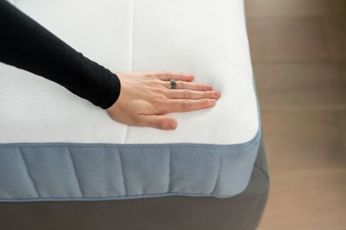 What Is Latex Mattress Made of? Hand pressing on a latex mattress surface to demonstrate the responsive, pressure-relieving feel of natural latex foam