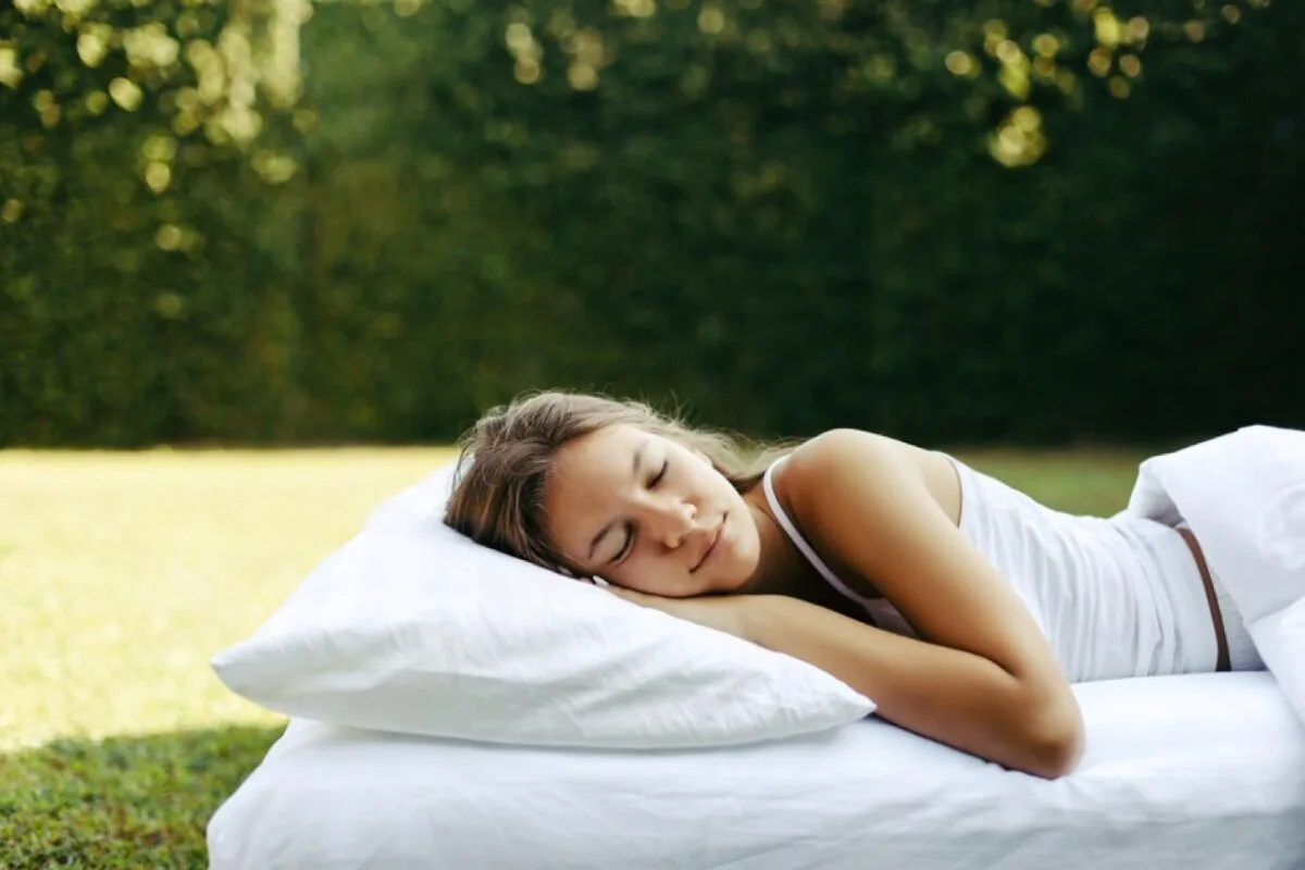 What Makes a Mattress Organic? A woman sleeping on a bed outside.