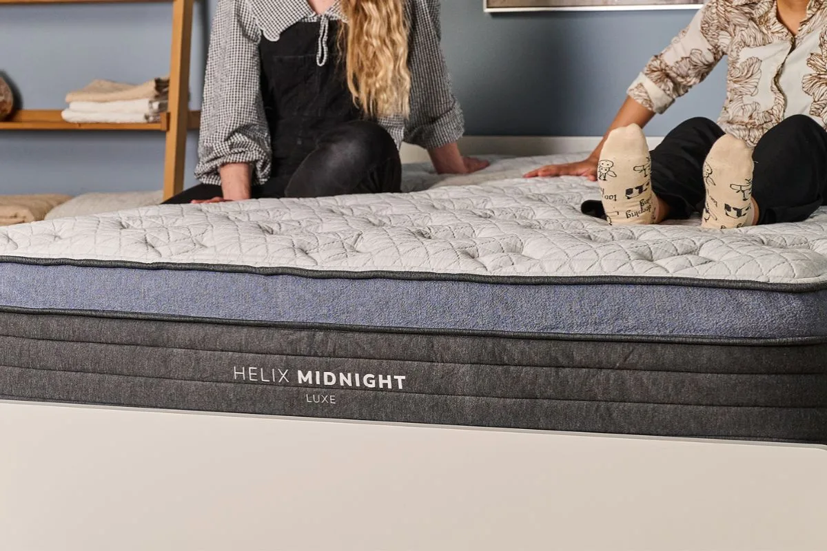 People sitting on the Helix Midnight Luxe mattress, demonstrating motion isolation and suitability for couples