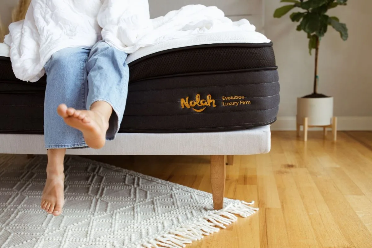 Person sitting comfortably on the edge of the Nolah Evolution 15 mattress, demonstrating strong edge support and ease of getting in and out of bed