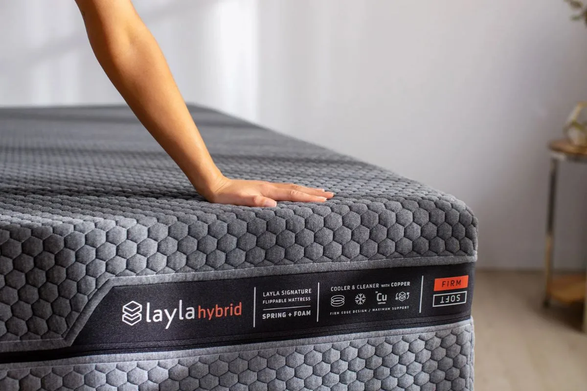 Hand pressing the Layla Hybrid Mattress to demonstrate comfort and support while evaluating whether to return the mattress during the sleep trial