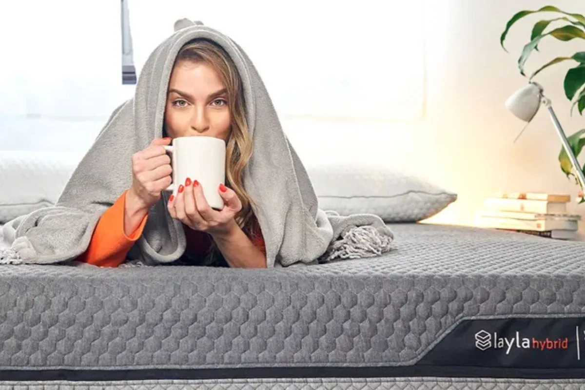 Person relaxing on the Layla Hybrid Mattress with a warm drink during the mattress trial period to evaluate everyday comfort at home