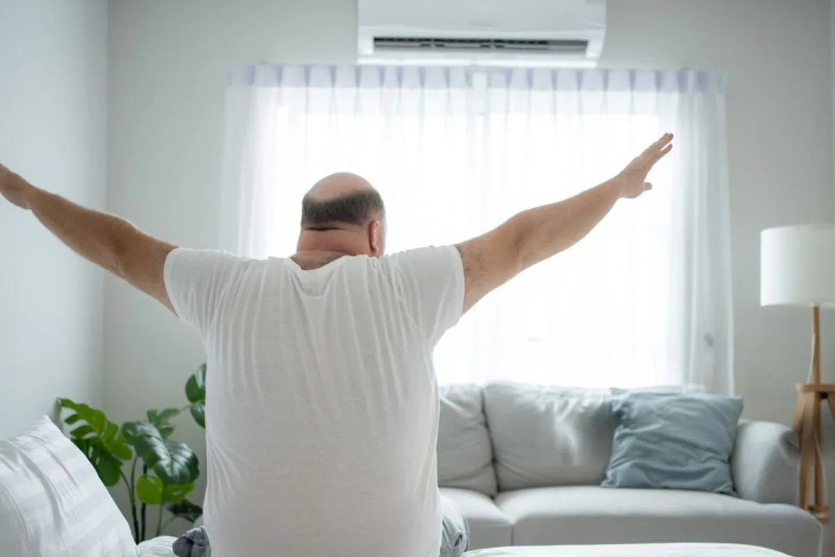 What Are The Disadvantages Of An Adjustable Firmness Mattress? Sleeper stretching after waking up, illustrating how mattress comfort and firmness can affect sleep quality and recovery