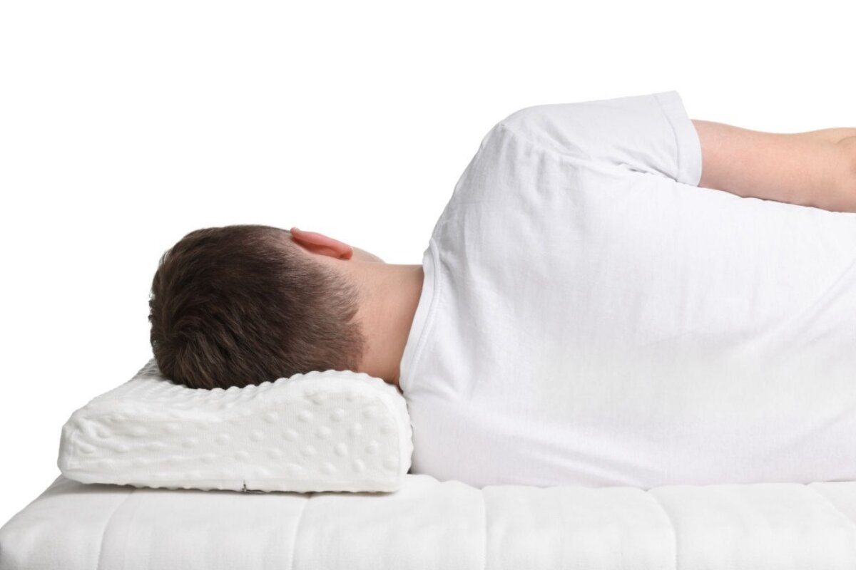 A man sleeping on his side on a mattress.